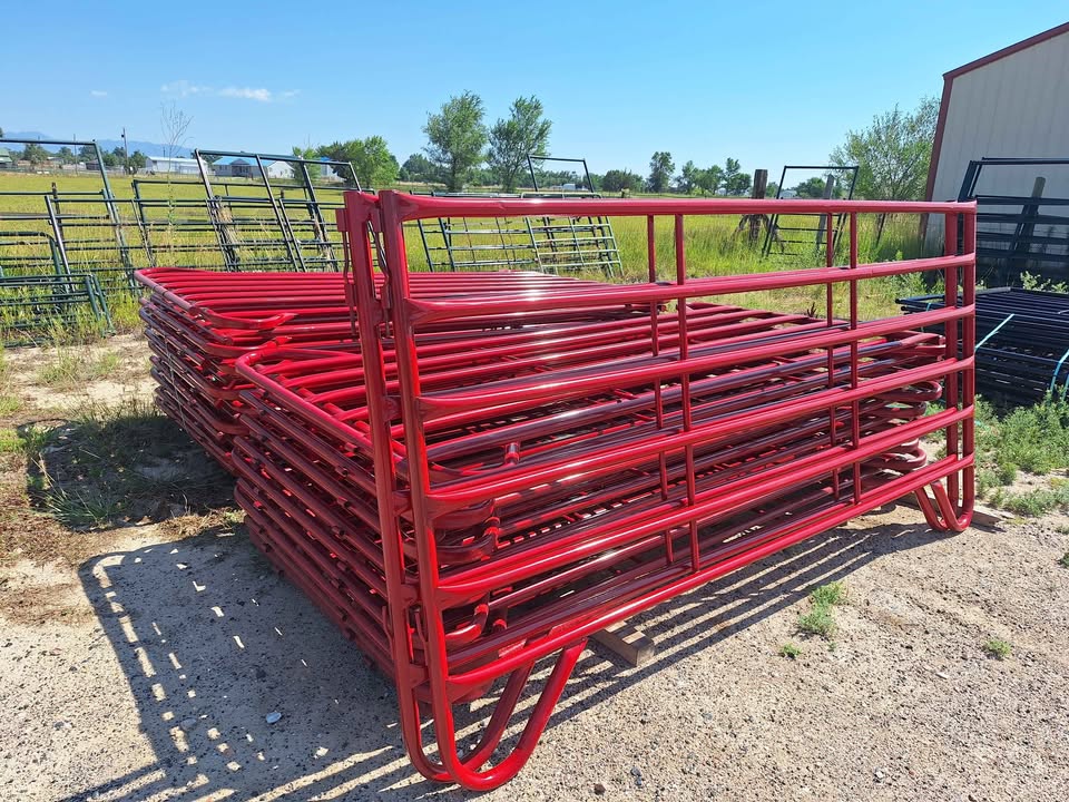 Stack of red powder-coated round-tube livestock panels